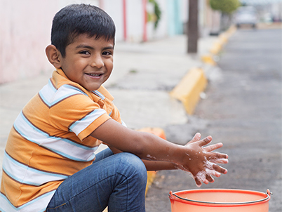 Boy sitting on the sidewalk with a bucket (photo)